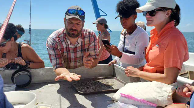 Teachers on a boat inspecting shells on a sorting table